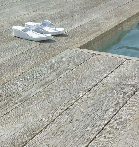 Terasové desky a hranové lišty Millboard Enhanced Grain Smoked Oak kolem bazénu.