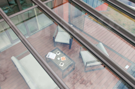 Pohled na vybavení terasy přes skleněnou střechu zastřešení Glasoase.